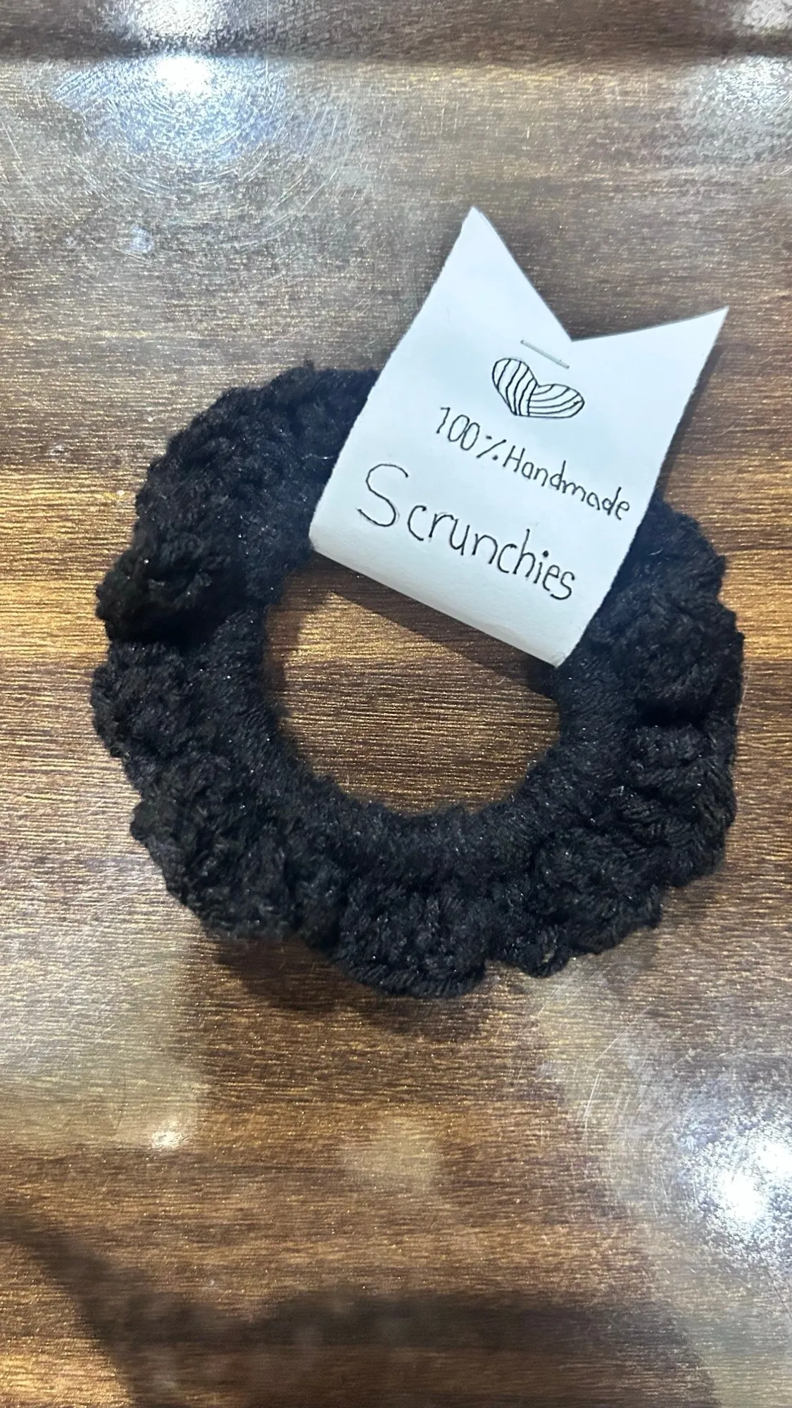 A soft, fluffy black crochet scrunchie