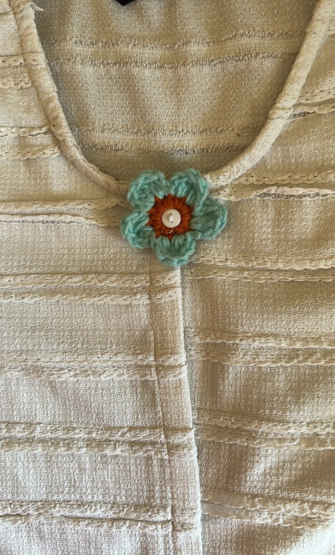 A mint crochet flower brooch with an amber center