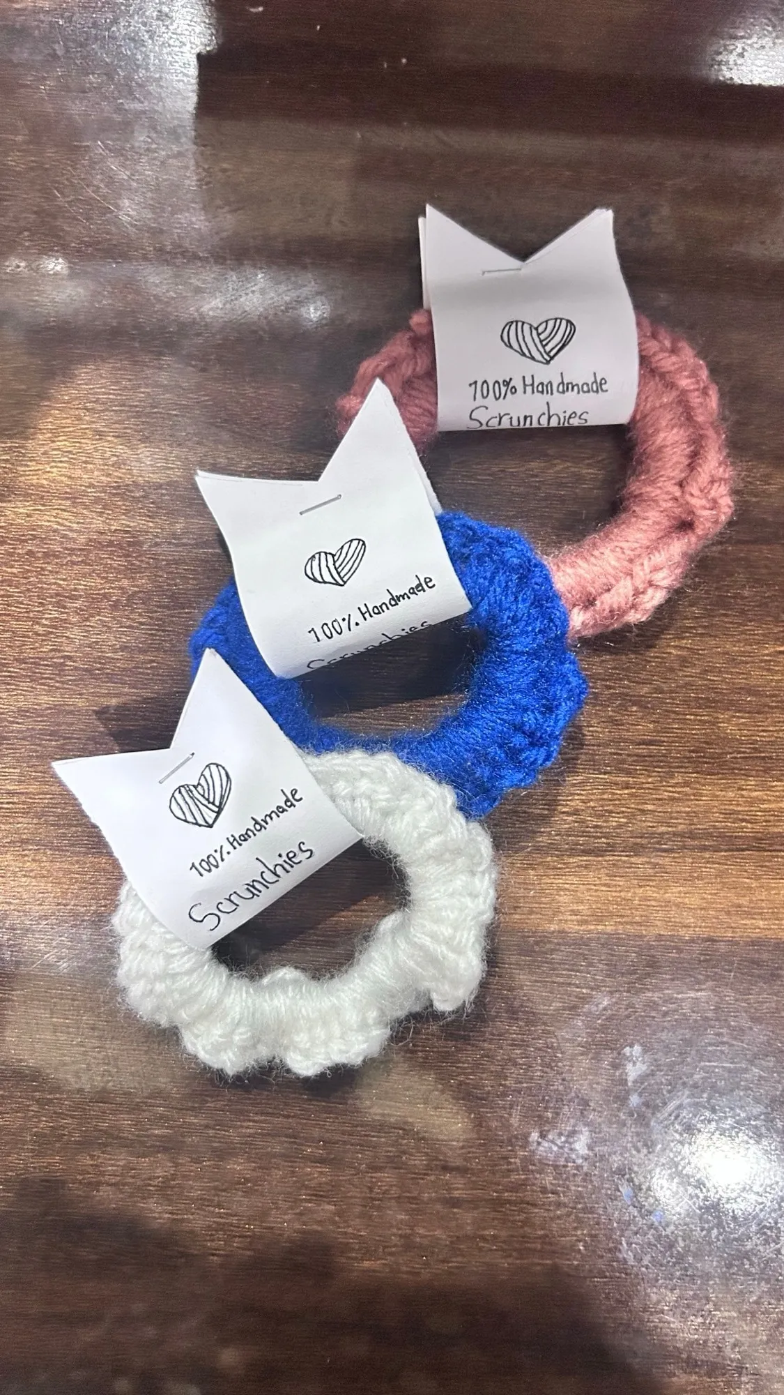 Three crochet scrunchies in rose, cobalt and ivory