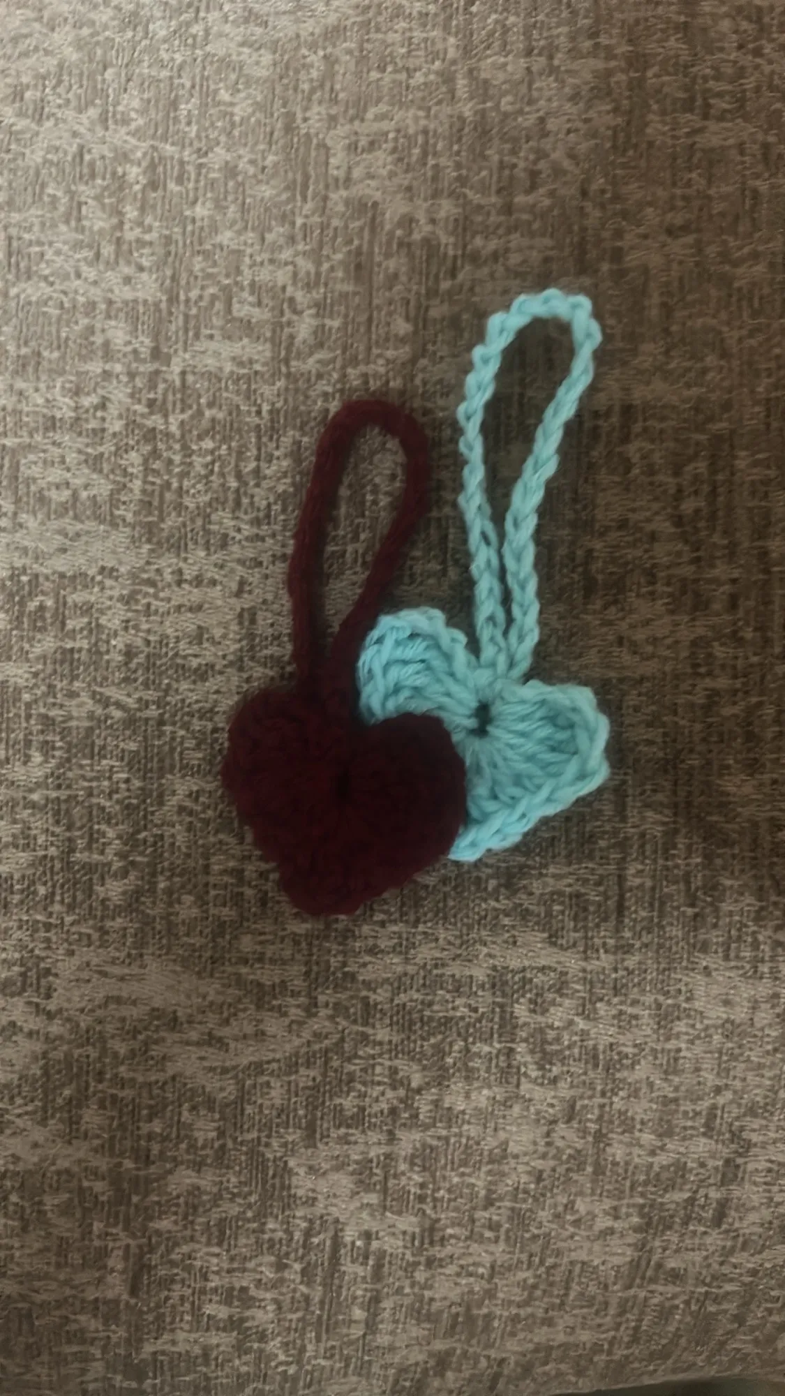 Two small crochet heart charms in burgundy and aqua