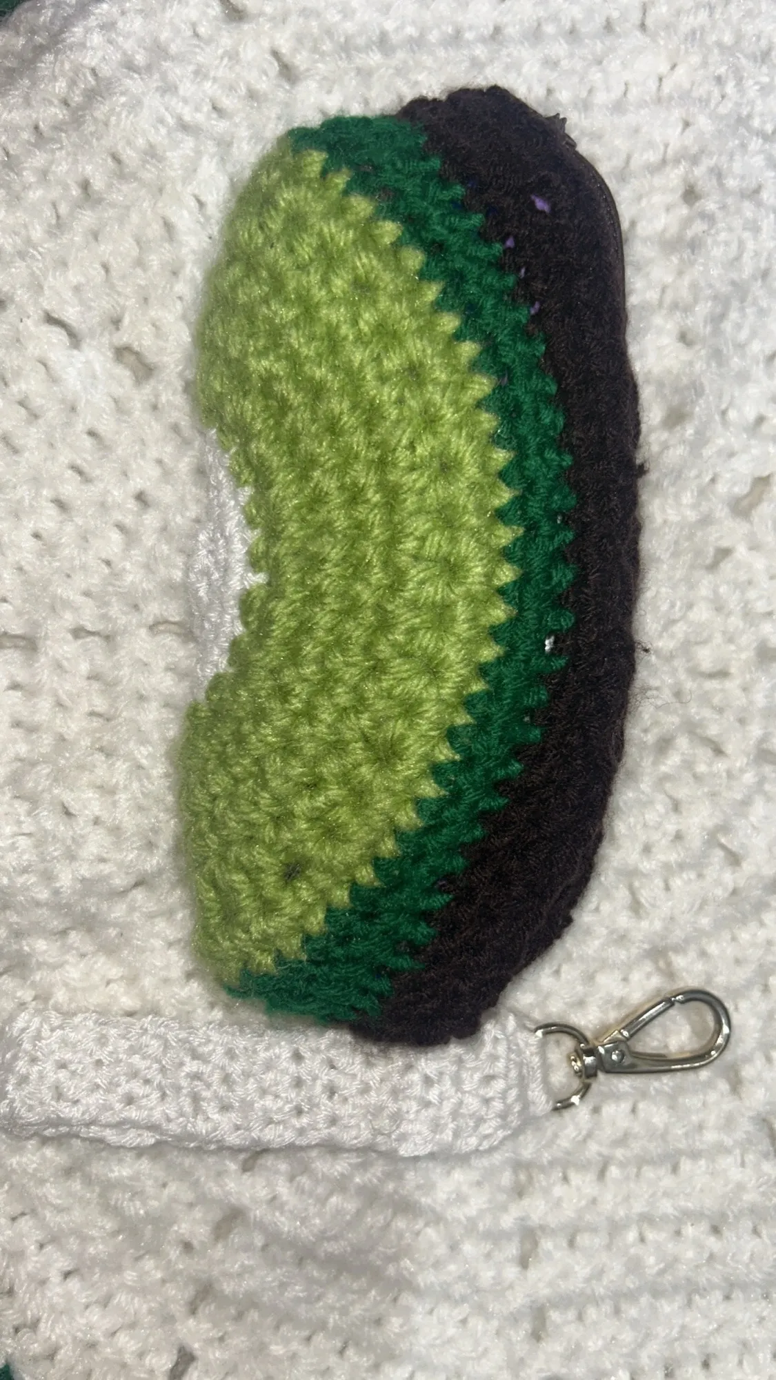 A crochet avocado keyring in layered greens