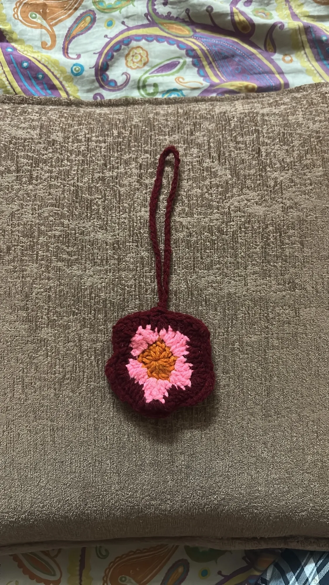 A handmade crimson crochet scrunchie with a neat ivory edge